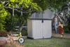 A girl runs past a storage box in a backyard while an older man watches. Voir les images du produit