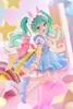 A figurine of Hatsune Miku dressed in a fairy tale-themed outfit, complete with bunny ears and holding a small pink creature, set against a whimsical, pastel-colored background with stars and rainbows. Produktbild-Vorschau