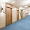 A long hotel corridor with multiple doors and blue carpet. Podgląd zdjęcia produktu
