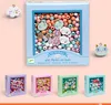 A collection of Djeco bead kits for jewelry making, displayed against a light pink background. The main focus is a large box of wooden beads with charms, and smaller boxes of themed beads are shown below. Anteprima dell’immagine prodotto