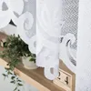 A close-up view of white lace curtains with a decorative pattern, draped over a wooden shelf with a potted plant and a wooden calendar block. Anteprima dell’immagine prodotto