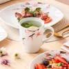 A table setting with a meal and drinks, featuring floral-patterned tableware. Voir les images du produit