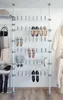A white telescopic shoe rack system with shoes on it, next to a wall with hanging clothes. Produktbild-Vorschau