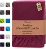 A folded burgundy fitted sheet with a product label wrapped around it, and a selection of other colored fitted sheets displayed in small squares on the left. Produktbild-Vorschau