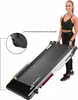 A woman is holding a folded treadmill. Voir les images du produit