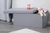 A grey storage ottoman with a partially opened lid, filled with stuffed animals. A patterned curtain is visible in the background. Náhľad obrázku produktu