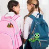 Two young girls wearing school uniforms and backpacks, one pink and one blue, are looking at each other. Each backpack has a colorful beaded animal charm attached. Náhled obrázku produktu