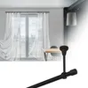 A black curtain rod with end cap is shown in the foreground, with a window with white sheer curtains and a dining table in the background. Podgląd zdjęcia produktu
