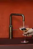 A hand is holding a glass of drink under a faucet, filling it with water. Podgląd zdjęcia produktu