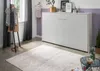 A bedroom scene with a white murphy bed against a purple and white wall, a clothing rack with clothes, and a rug on the floor. Produktbild-Vorschau