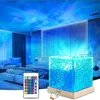 A bedroom with a projector lamp creating aurora and wave light effects on the ceiling and walls. A cube-shaped lamp with a wood base is on a nightstand. Anteprima dell’immagine prodotto