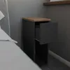 A close-up view of a narrow gray bedside table with a wooden top and one open drawer, placed next to a bed. Produktbild-Vorschau