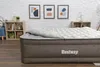 An inflatable mattress with a duvet is set up in a room with decorative artwork on the wall and shelving units. Produktbild-Vorschau