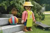 A large Playmobil figure of a gardener is standing in a garden setting next to a ball and a skateboard. Podgląd zdjęcia produktu