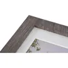 A close-up view of a picture frame with a textured gray wood finish and a white matting. Produktbild-Vorschau