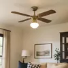 A ceiling fan with a light fixture is shown in a living room setting. Náhľad obrázku produktu