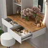 A vanity table with drawers open, displaying makeup and accessories, with flowers and a stool. Voir les images du produit