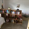 A room with a bookshelf made of wooden crates, filled with books and plants. Náhled obrázku produktu