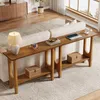 A long, narrow console table with two shelves is placed behind a white sofa in a living room. The table is made of light walnut wood and has decorative cutouts in its legs. It is decorated with a lamp, a vintage camera, books, a laptop, a cup of coffee, an Anteprima dell’immagine prodotto