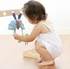 A baby playing with a toy attached to a wooden play gym. Produktbild-Vorschau