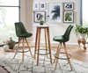 A modern bar area with a high table and two bar stools, decorated with plants and framed art. Produktbild-Vorschau
