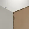 Close-up of the corner of a white furniture piece, showing the edge and the particle board backing attached with staples. Náhled obrázku produktu