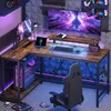 A gaming setup with an L-shaped desk, multiple monitors, a computer tower, and a gaming chair, all illuminated by colorful LED lights. Anteprima dell’immagine prodotto