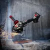 An angle grinder is shown in action, cutting a metal pipe, with sparks flying. The background is a rough concrete wall and rocky ground. Produktbild-Vorschau