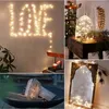 A collage of four images showcasing decorative string lights in various settings, including spelling out 'LOVE' on a wall, inside a glass dome, around a mirror, and with firewood. Produktbild-Vorschau
