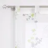 A close-up view of a sheer curtain with a floral pattern hanging on a curtain rod. Produktbild-Vorschau