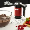 A red and black hand mixer with beaters, next to a bowl of chocolate batter and berries. Produktbild-Vorschau