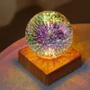 A decorative LED lamp with a glass sphere on a wooden base, casting colorful light patterns. Produktbild-Vorschau