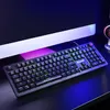 A gaming keyboard is placed on a desk in front of a computer monitor, with colorful LED lighting illuminating the scene. Produktbild-Vorschau