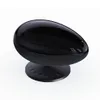 A black, egg-shaped projector on a black circular base, set against a white background. Produktbild-Vorschau