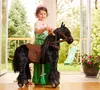 A young girl in a princess dress is playing with a black toy horse on wheels in a backyard setting. Náhľad obrázku produktu