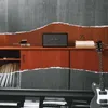 A Marshall speaker sits on a wooden cabinet next to books and a guitar, with a torn paper effect revealing a grey background. Produktbild-Vorschau