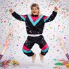 A man in a retro tracksuit jumping in the air surrounded by confetti. Voir les images du produit