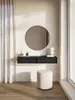 A minimalist vanity setup with a floating black console, round mirror, decorative vase, and a round stool. Anteprima dell’immagine prodotto