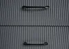 A close-up view of two drawers of a gray cabinet with ribbed texture and black handles. Produktbild-Vorschau
