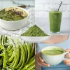 A collage of four images showing different ways to use or present green powder, including a smoothie bowl, a glass of green smoothie, a pile of green powder, green pasta, and a cup of green tea. Produktbild-Vorschau