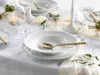 A formal table setting with white porcelain plates, glasses, and cutlery, illuminated by candlelight. Náhľad obrázku produktu