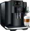 A black Jura E8 coffee machine with a glass of latte macchiato in the foreground. Podgląd zdjęcia produktu