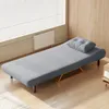 A gray sofa bed with a pillow is placed in a room with a window and wooden walls. Náhľad obrázku produktu