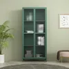 A green glass-door cabinet filled with decorative items, placed in a room with light green walls and wooden floor. Podgląd zdjęcia produktu
