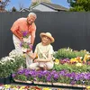 A couple is gardening in front of a fence. Produktbild-Vorschau