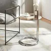 A glass-top side table next to a chair, with a book and cup on the table. Anteprima dell’immagine prodotto
