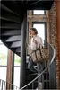 A woman walks up a spiral staircase carrying a leopard print cooler bag. Náhled obrázku produktu