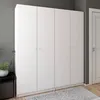A white wardrobe with four doors is shown in a room with patterned wallpaper and a rug. Náhled obrázku produktu