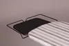 A close-up view of a black metal ironing board accessory attached to a striped ironing board cover. Produktbild-Vorschau