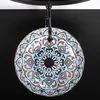 A decorative ceramic sink with a mandala pattern, suspended from a black fixture against a black background. Náhled obrázku produktu